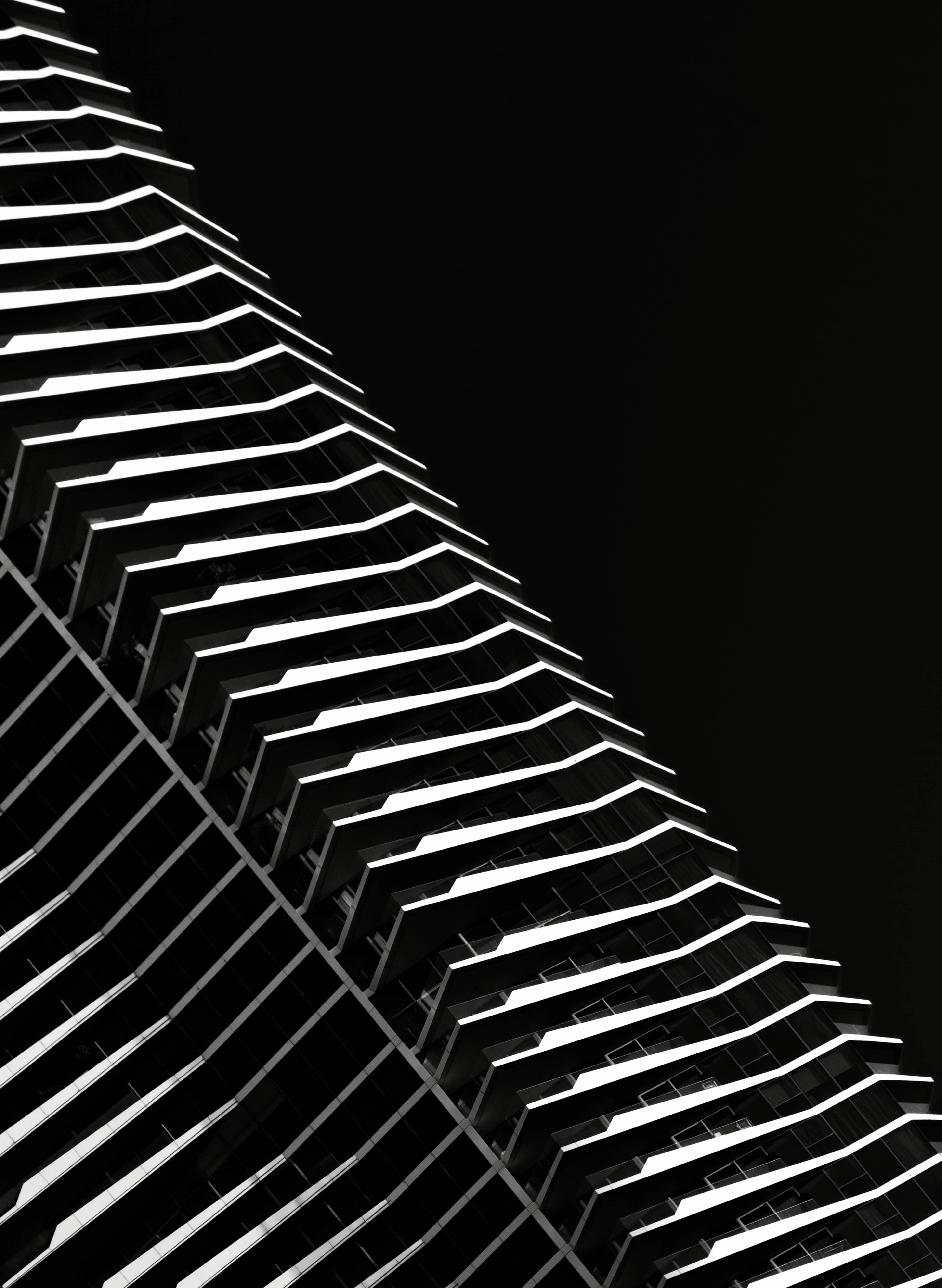 A high-rise facade reduced to luminous repeating edges against black.