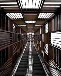 A long symmetrical escalator enclosed by repeating geometric screens.