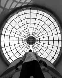 A figure seen from below between symmetrical ribbed concrete structures.